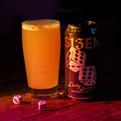 A hazy beer in a glass with dice next to it